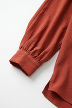 Close-up mouw en manchet van terracotta blouse