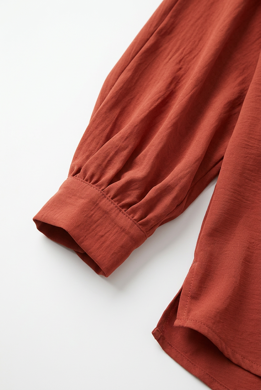 Close-up mouw en manchet van terracotta blouse